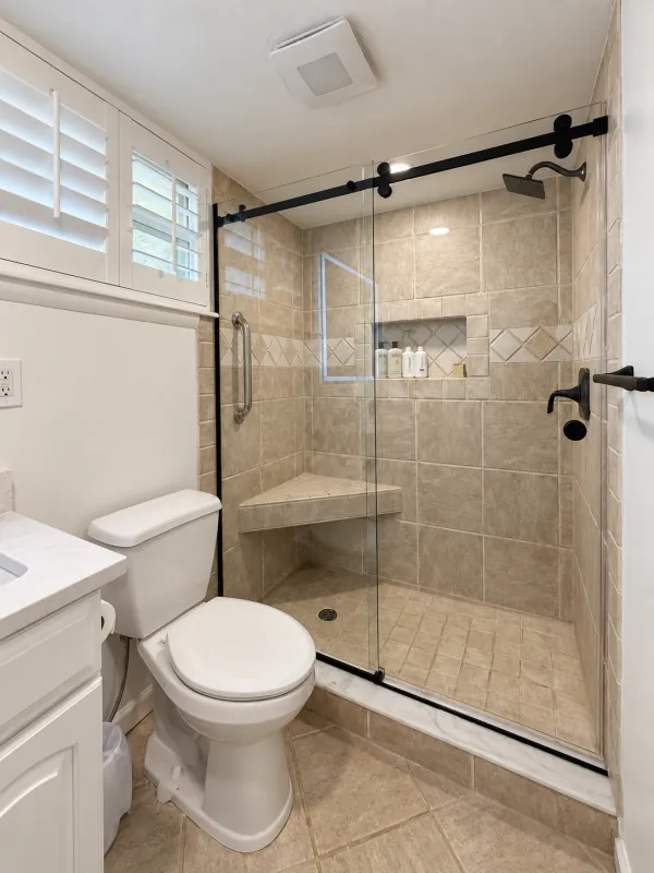Black sliding shower doors with a tiled bench