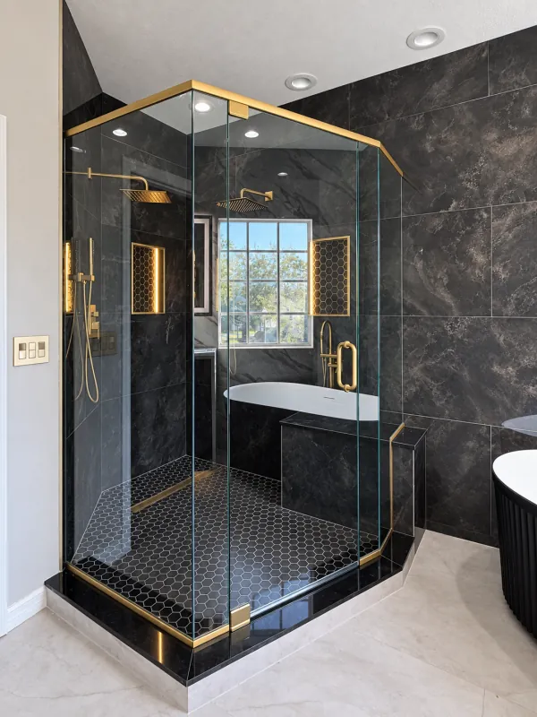 Angled glass enclosure with brass hardware and dark tile