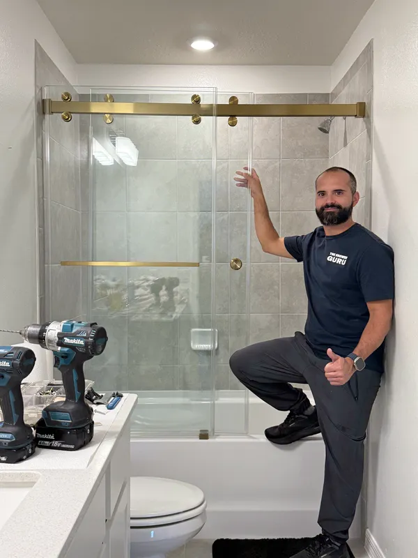 Brass sliding glass doors over a tub, installed by Gabriel