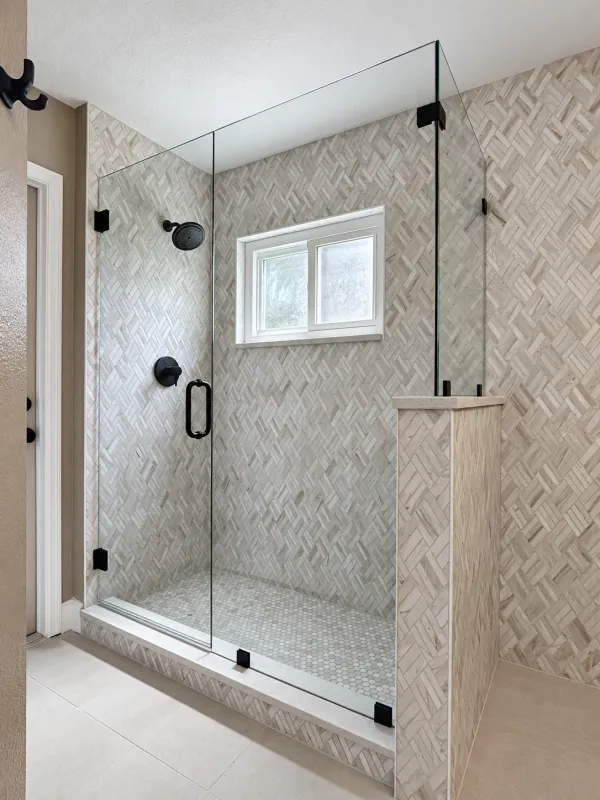 Black-hardware glass shower with herringbone tile
